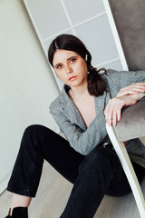 Beautiful fashionable brunette woman in a grey jacket and black trousers in the photo studio