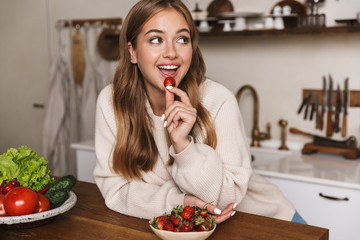 Sticker - Image of happy caucasian woman eating strawberry and smiling