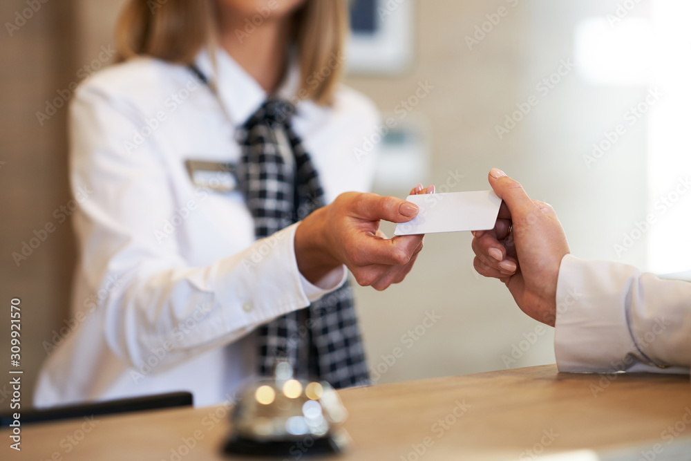 Receptionist giving key card to businesswoman at hotel front desk - obrazy, fototapety, plakaty 