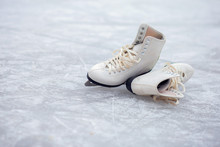 A Pair Of White Figure Skates Lie On An Open Ice Rink
