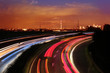 © kittyfly - Traffic with motion cars with luminous lines of speed and the evening European city of Frankfurt with beautiful sunset sky, cityscape