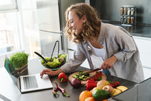 Happy Young Woman Making A Salad At The Kitchen