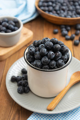 Wall Mural - Ripe blueberries in metalic cup on the wooden table. Fresh berries for breakfast. Copy space.