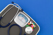 © Valerii Evlakhov - Scale, stethoscope and drugs on blue background. Loose weight and healthcare concept.