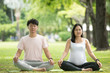 © nareekarn - pregnant woman and man are sitting in yoga pose and doing breathing exercise together