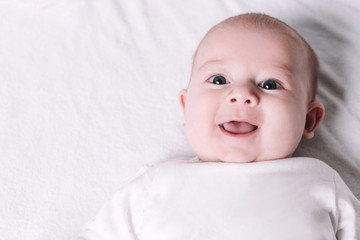 cute smiling baby lying on the bed.