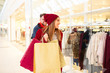 © Sanja - Young cheerful caucasian couple smiling and having fun while doing some Christmas shopping and passing by shop window in shopping mall. Girlfriend is carrying a few shopping bags.