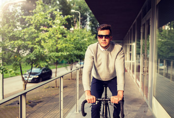 Wall Mural - lifestyle, transport and people concept - young man in sunglasses riding bicycle on city street