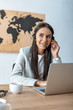 © LIGHTFIELD STUDIOS - smiling travel agent working near laptop