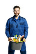 Attractive young man  in cleaning uniform holding  a bucket of cleaning products in his hands, isolated on white background.