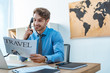 © LIGHTFIELD STUDIOS - smiling travel agent talking on phone while holding travel newspaper