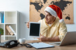 © LIGHTFIELD STUDIOS - surprised travel agent in santa hat holding digital tablet with blank screen