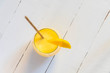 Top view of indian traditional drink Mango Lassi with paper straw and mango slice on white wooden table