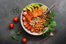 Bowl Of Healthy Vegan Salad On A Dark Rustic Background. Salad Of Fried Chickpeas, Quinoa, Avocado, Fried Sweet Potatoes And Tomatoes. Top View.