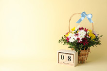 Wicker Basket With Flowers And Wooden Calendar On Beige Background, Space For Text
