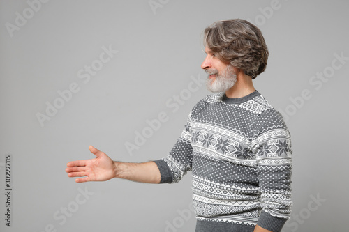 Side View Of Elderly Gray Haired Mustache Bearded Man In Knitted Sweater Posing Isolated On Grey Background People Lifestyle Concept Mock Up Copy Space Standing With Outstretched Hand For Greeting Stock Photo Side View Of Elderly Gray Haired Mustache Bearded Man In Knitted Sweater Posing Isolated On Grey Background People Lifestyle Concept Mock Up Copy Space Standing With Outstretched Hand For Greeting Stock Photo