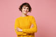 © ViDi Studio - Smiling young brunette woman girl in yellow sweater posing isolated on pastel pink background studio portrait. People sincere emotions lifestyle concept. Mock up copy space. Holding hands crossed.