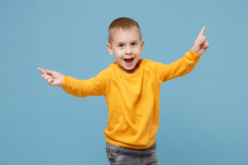 Wall Mural - Little cute kid boy 4-5 years old wearing yellow clothes isolated on pastel blue wall background, children studio portrait. People sincere emotions, childhood lifestyle concept. Mock up copy space.