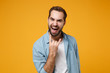 © ViDi Studio - Crazy young bearded man in casual blue shirt posing isolated on yellow orange background studio portrait. People lifestyle concept. Mock up copy space. Showing horns up gesture, heavy metal rock sign.