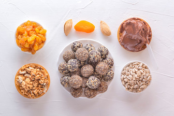 Natural healthy raw energy bites, chocolate paste and mix of dried fruits with nuts on a white table. Top view