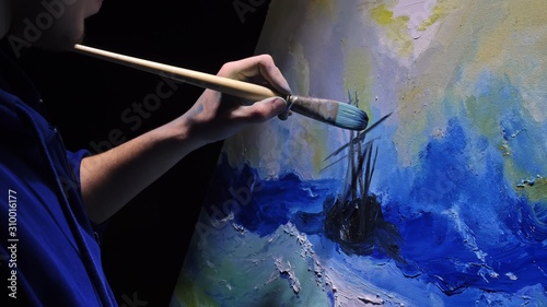 Artist copyist paint seascape with ship in ocean. Craftsman decorator draw as boat sail on blue sea with acrylic oil color. Draw finger, brush, knife palette. Indoor. Dark magic cinematic look.