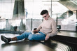 © GalakticDreamer - Smiling young man in glasses working on laptop and sitting on floor