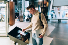 Young Casual Man Using Modern Information Stand In Hall