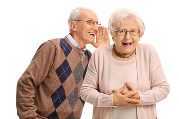 Wall Mural - Senior man whispering to a senior woman