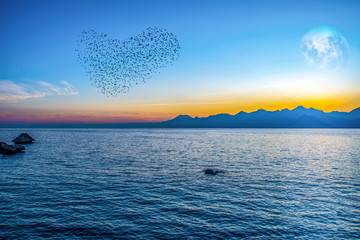 Wall Mural - Silhouetted people relaxing in Antalya harbor over sunset sky and high mountains