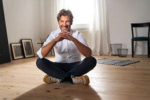 Portrait Of Smiling Mature Man Sitting On The Floor At Home