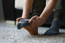 Man At Home In Morning Puts Gray Socks On His Leg