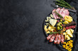Typical italian antipasto with prosciutto, ham, cheese and olives. Black background. Top view. Space for text