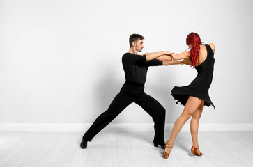 Wall Mural - Beautiful young couple dancing near light wall. Space for text