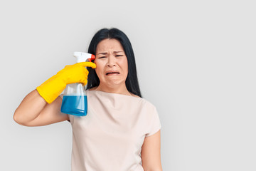 Freestyle. Asian woman in gloves standing isolated on white with spray near head grimacing unhappy