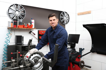 Wall Mural - Man working with car disk lathe machine at tire service