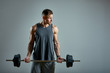 Man doing back workout, barbell row in studio over gray background. Copy space