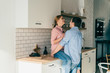 © GalakticDreamer - Man hugging woman sitting on table in kitchen