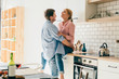 © GalakticDreamer - Cheerful couple embracing in kitchen