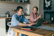 © GalakticDreamer - Couple sitting at table with laptop in kitchen