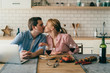 © GalakticDreamer - Couple kissing at table with laptop in kitchen