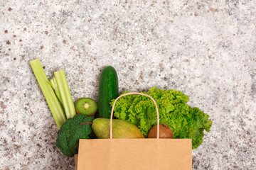 paper shopping bag with green health food on the gray backgraund. vegan and vegetarian concept. close up, copy space