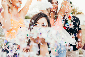 Wall Mural - Brazilian Carnival. Young woman in costume enjoying the carnival party blowing confetti