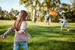 © Svitlana - Here we go again. Little girl playing frisbee with her family in the park on a sunny day
