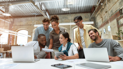 We have great results. Group of young cheerful business people in casual wear working together on new project while sitting in the creative office