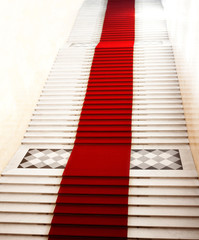 Staircase with red carpet, illuminated by light