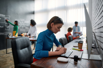 Wall Mural - professional graphic designer. side view of young creative woman using digital graphics tablet while