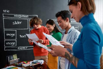Wall Mural - creative team. group of four cheerful web designers in casual wear developing new web site layout wh