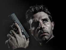 Closeup Portrait Of Serious And Attractive Hitman Or Special Agent Man Holding Gun Isolated On Black Background In Secret Service Hollywood Style Movie And Cinematic Lighting
