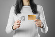© Dima Plotnikov - The girl holds a condom and birth control pills. Close up. Isolated on grey background