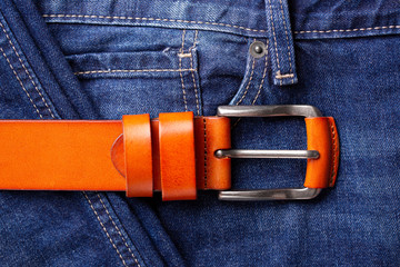 Fashionable leather belt and jeans top view. Leather belt and blue jeans close-up. Belt accessory.